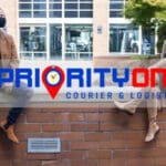 Two people sitting on a brick wall with the priority one logo in front of them.