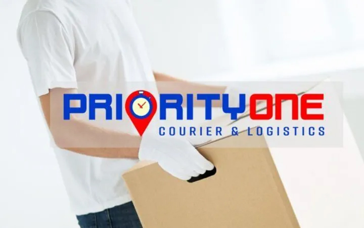 A person holding a box in front of the priority one logo.